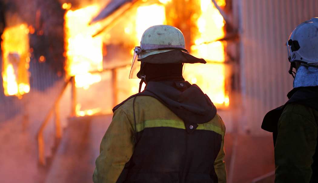 Pelastajat seisovat palavan talon edessä.