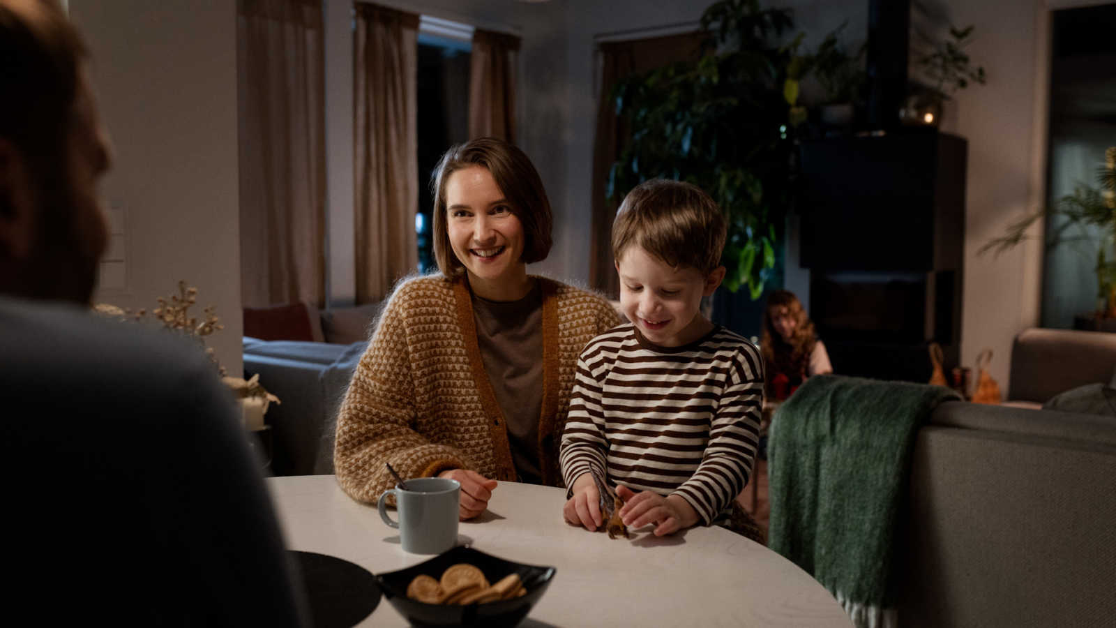 Äiti ja lapsi istuvat pöydän ääressä hymyillen.