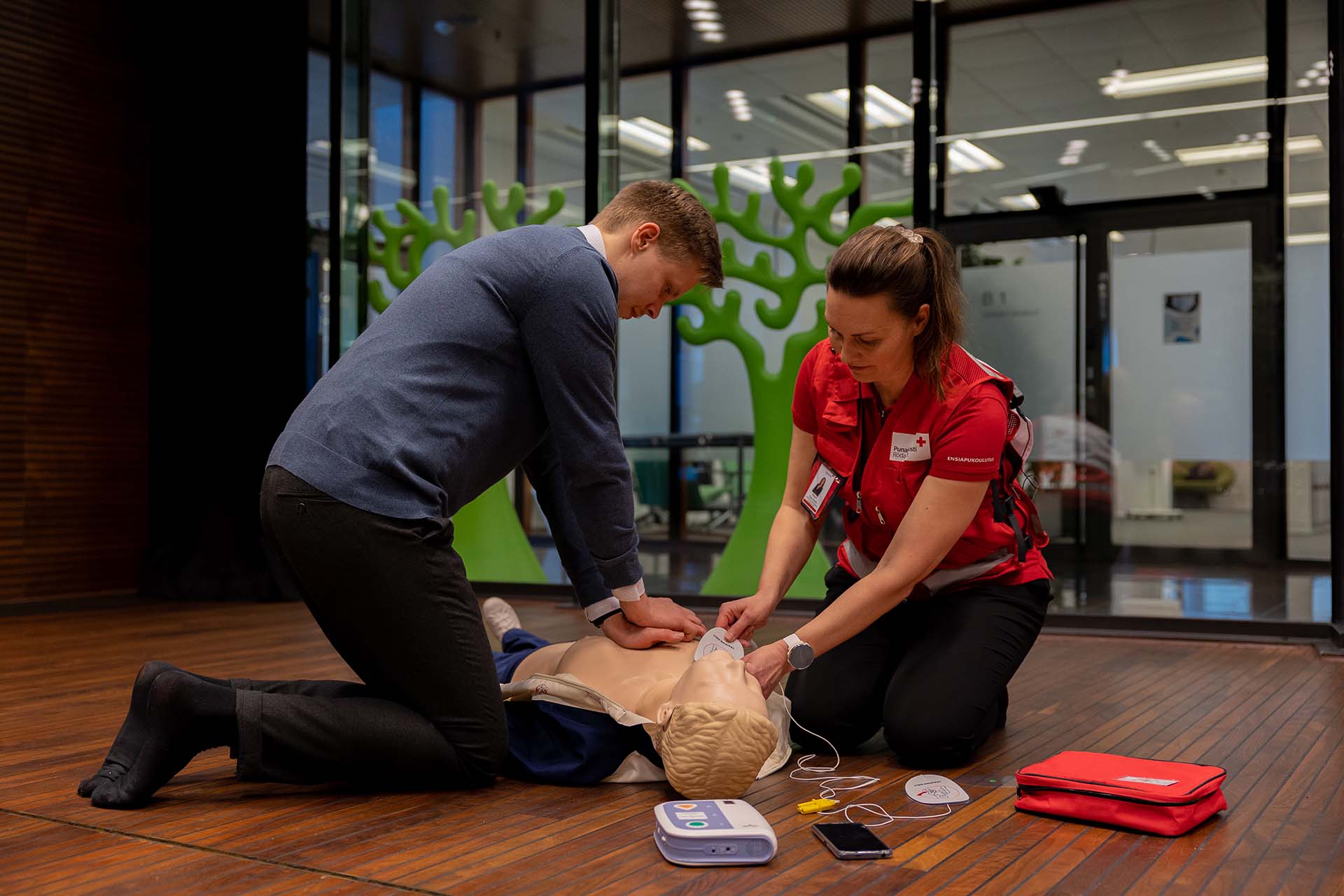 Ensiapukouluttaja ja mies harjoittelevat paineluelvytystä.
