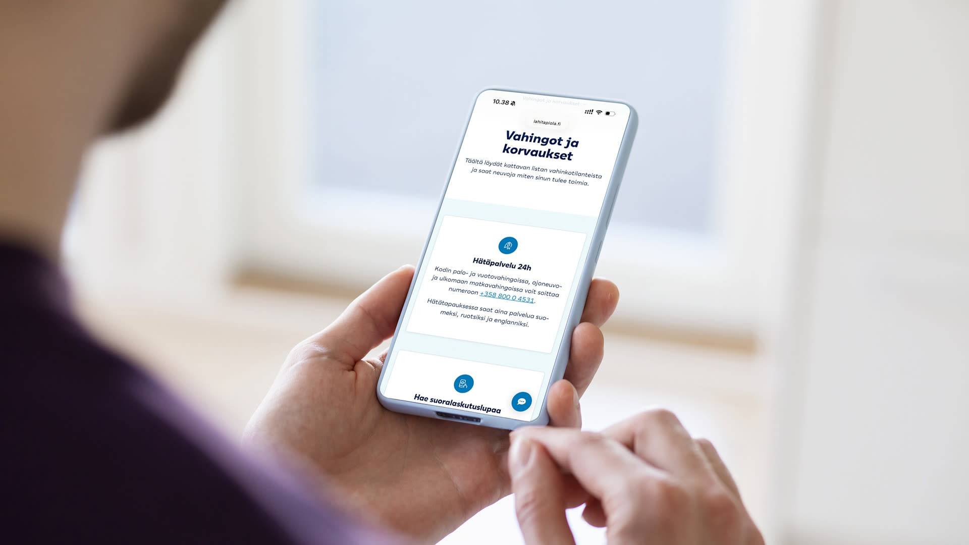Henkilö tutkii puhelimesta LähiTapiolan hätäpalvelun yhteystietoja