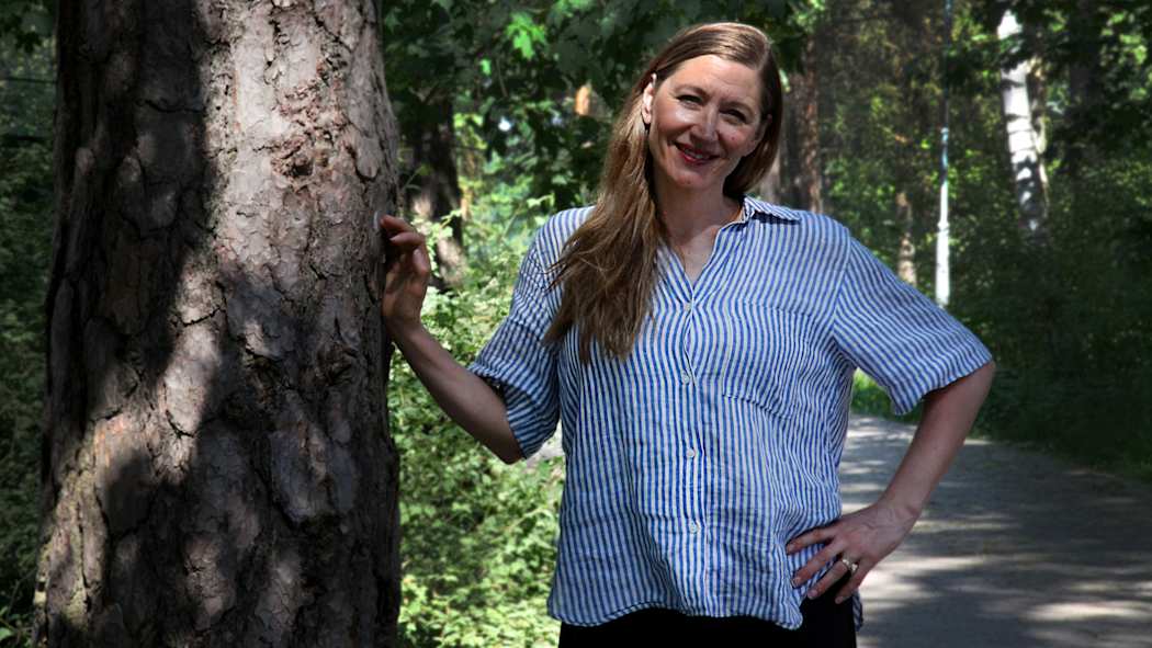 Merja Mähkä hymyilee aurinkoisella metsäpolulla.