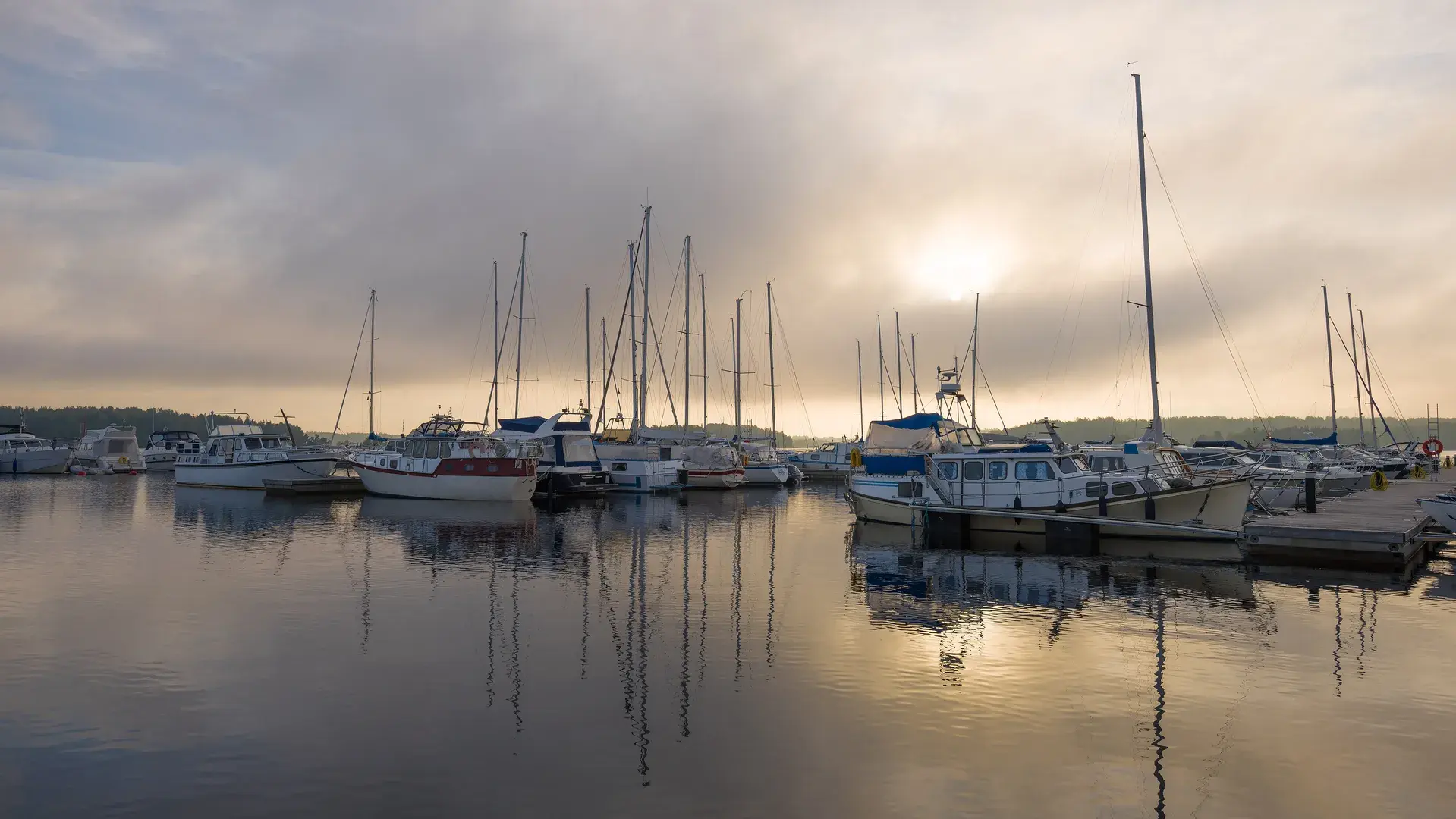 Purjevene seilaa järvellä puolipilvisenä kesäpäivänä.