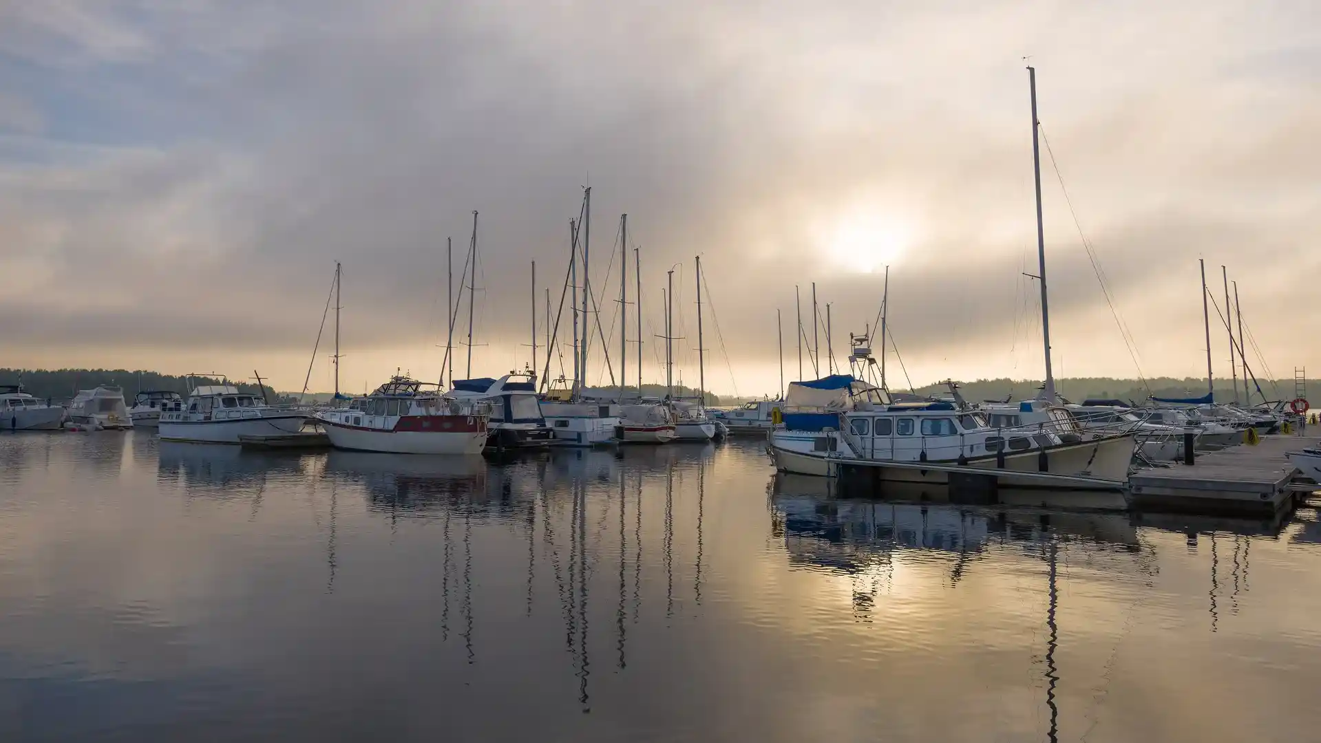 Purjevene seilaa järvellä puolipilvisenä kesäpäivänä.