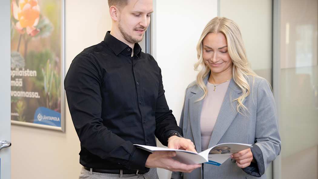 Työkaverit tutkivat yhdessä vakuutusesitettä.