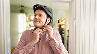 Mies kiinnittää pyöräilykypärää sisätiloissa